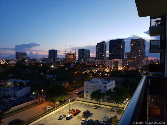 Panoramic view of a cityscape at dusk with illuminated high-rise buildings.