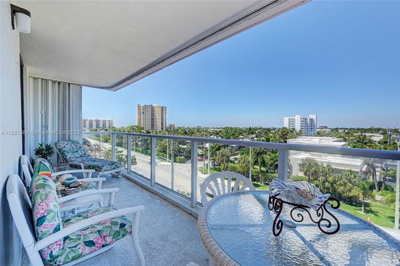 Balcony view overlooking cityscape with chairs and table.