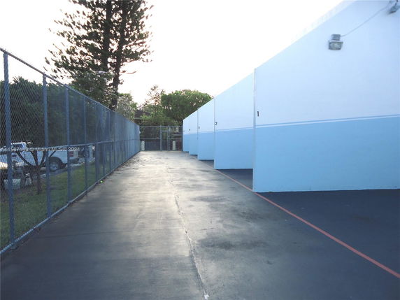 Outdoor concrete area with numbered walls and a fenced perimeter.