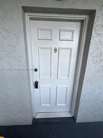 Front view of a white residential door with decorative panels and a peephole.