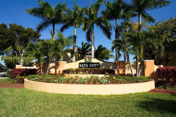 Entrance sign for a residential community with landscaping and palm trees.