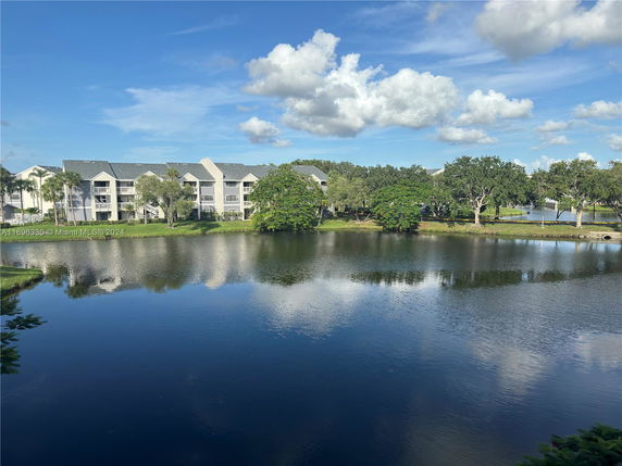 Residential building surrounded by trees and a body of water.