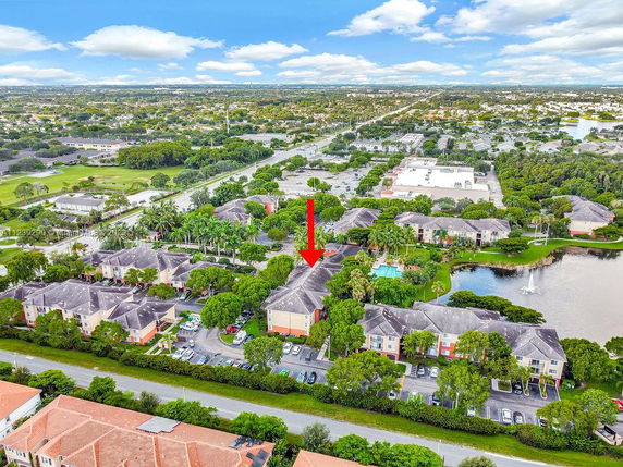 Aerial view of a residential area with multiple buildings, roads, and a small body of water.