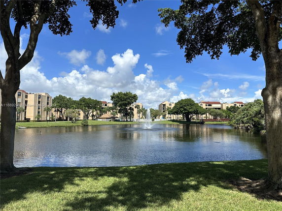 View of a residential area with multiple buildings surrounding a pond with a fountain.