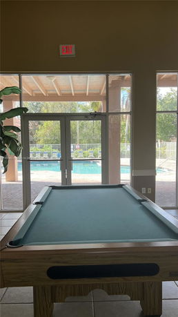 Room with a pool table and glass doors leading to an outdoor area.