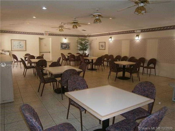 Room with multiple tables and chairs, ceiling fans, and wall art.