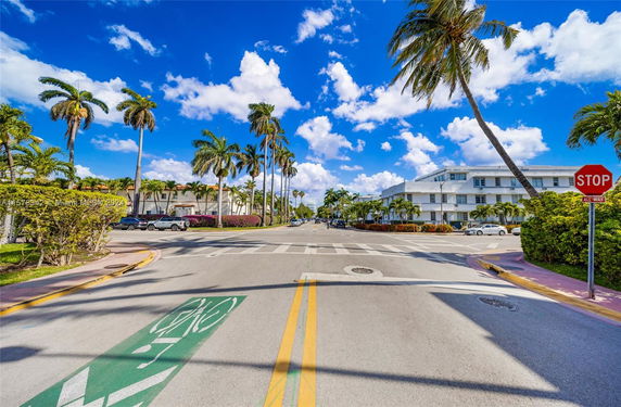 Street view with a crosswalk, palm trees, and surrounding buildings.