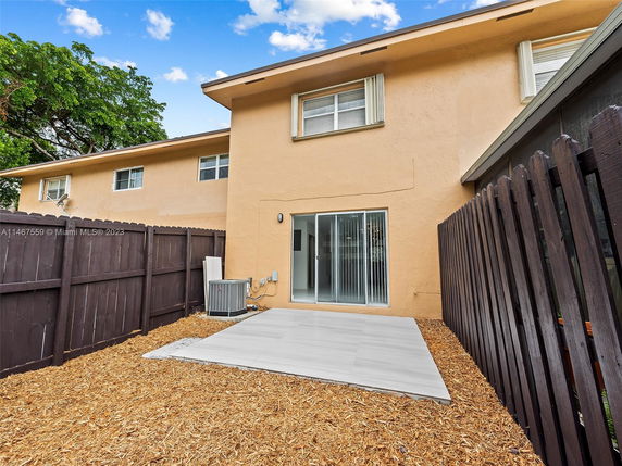 Back view of a two-story house with a fenced yard and sliding glass door.