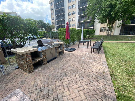 Outdoor area with a barbecue grill and a dining table with chairs on a paved patio.