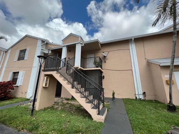 Front view of a two-story building with an external staircase leading to an upper balcony.