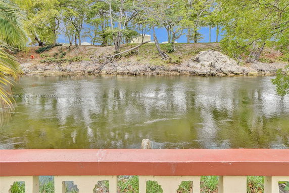 View of a river with trees on the opposite bank and a railing in the foreground.