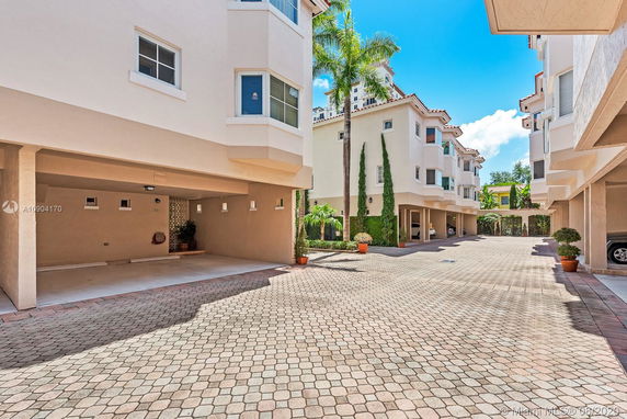 Outdoor parking area between residential buildings with covered parking spots.