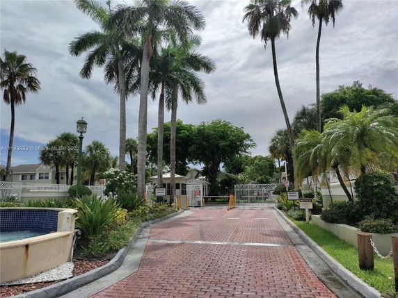 Entrance view of a residential community with palm trees and a gated entry.