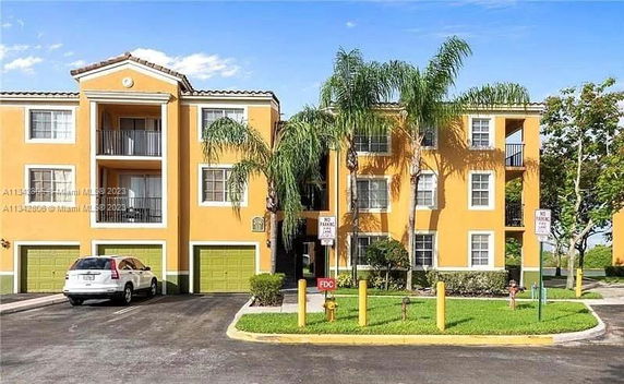 Front view of a multi-story residential building with a yellow facade and green doors.