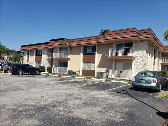 Front view of a two-story apartment building with balconies and parking area.