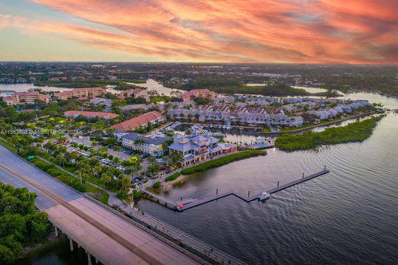 Aerial view of a waterfront residential area with houses, roads, and a bridge.