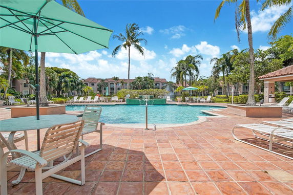 Outdoor swimming pool area with lounge chairs and umbrellas.