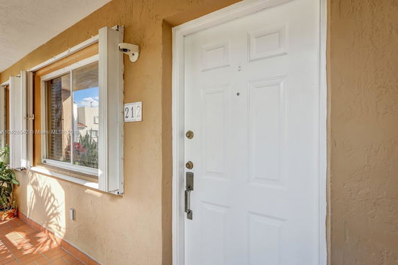 Front view of a house entrance with a white door and a window with shutters.