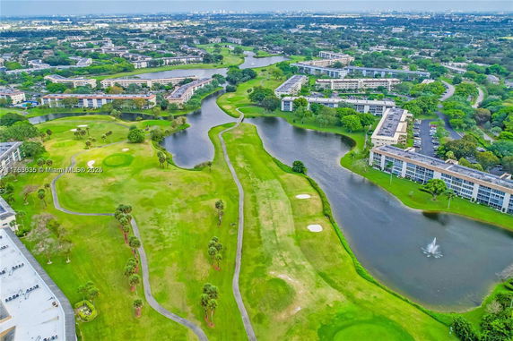 Aerial panoramic view of a golf course surrounded by residential buildings and water features.
