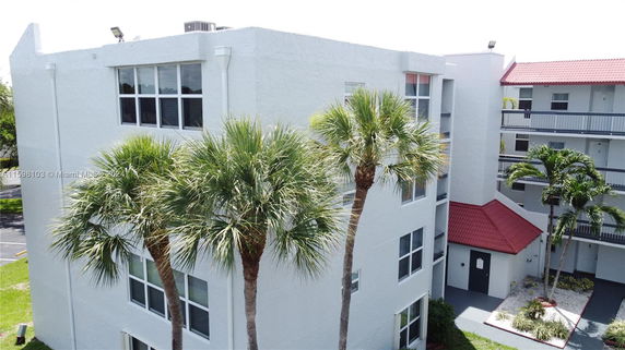 Elevated view of a white multi-story residential building with red roof accents.