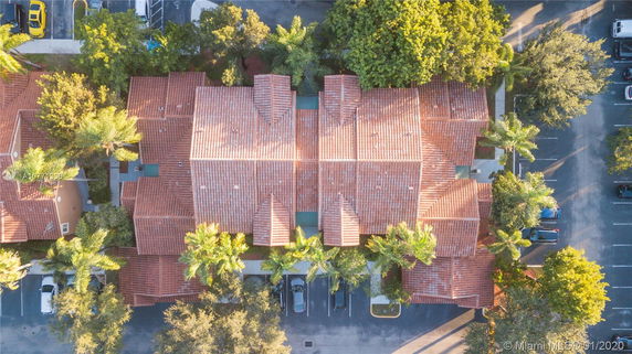 Aerial view of a building with red tiled rooftops and surrounding trees.