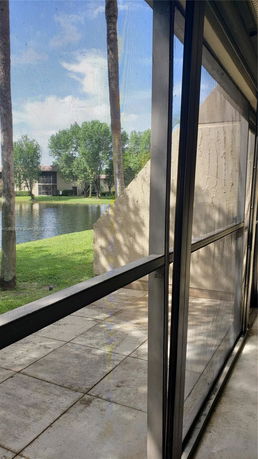 View from a building showing a patio area with a lake and trees in the background.