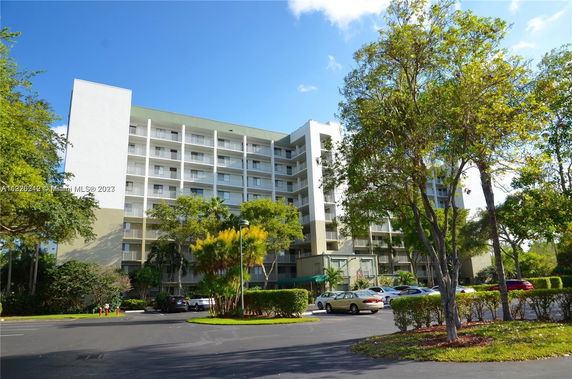 Front view of a multi-story residential building with a parking lot in front.