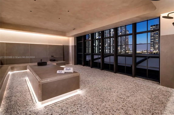 Interior view of a modern spa or wellness area with tiled surfaces and large windows.
