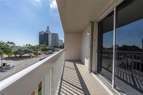 Balcony overlooking a street with tall buildings and palm trees in the background.
