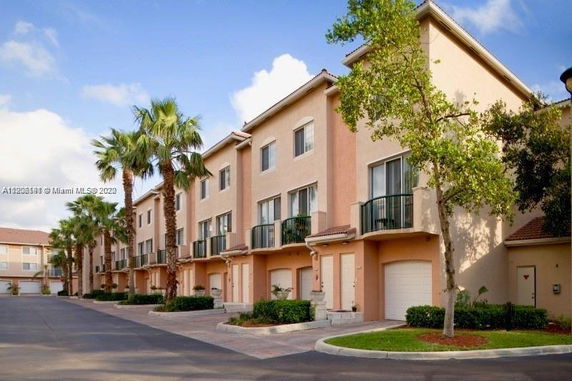 Front view of a row of multi-story townhouses with balconies and garages.