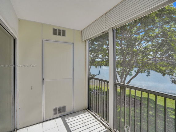 Enclosed balcony with view of trees and a lake.