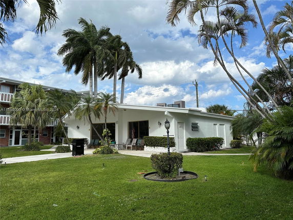 Front view of a single-story house with palm trees and a patio area.