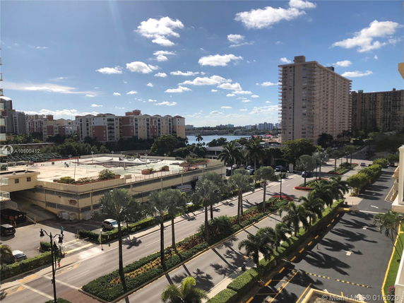 View of multiple residential buildings and roads with palm trees, seen from a building.