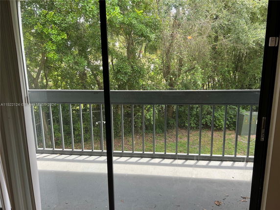 View from a building balcony showing a lush green area with trees.