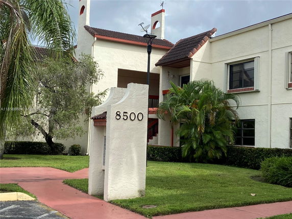 Front view of a two-story building with a tile roof and a prominent street number sign.