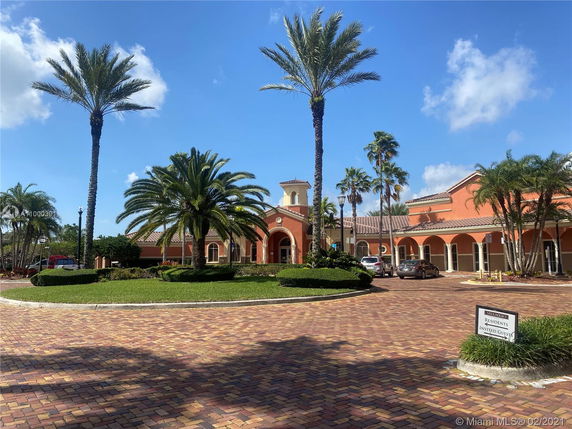 Front view of a Mediterranean-style building with arches and palm trees.