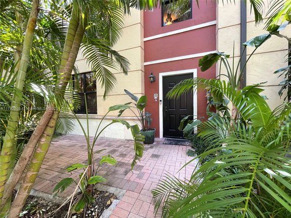 Front view of a house with a black entrance door and surrounding plants.