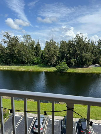 View from a balcony overlooking a river and parking area.