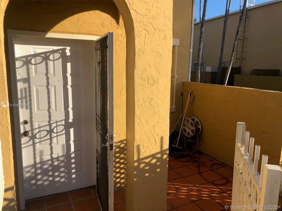 Entrance area with an open white door and decorative metal gate.