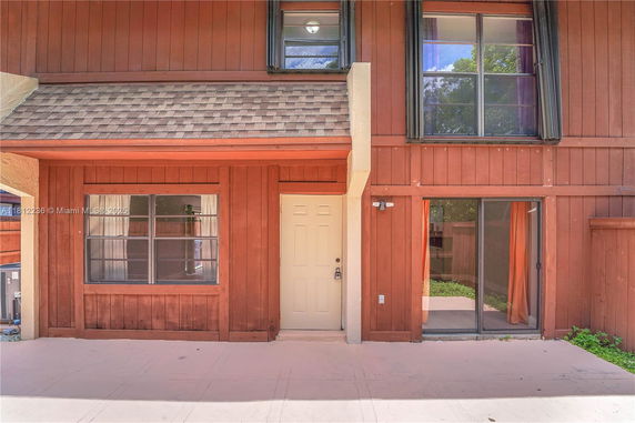 Front view of a two-story house with large windows and a shingled roof.