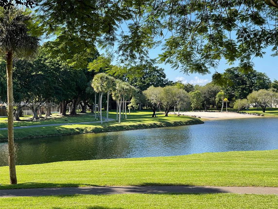 Scenic view of a park area with a lake and trees in the background.