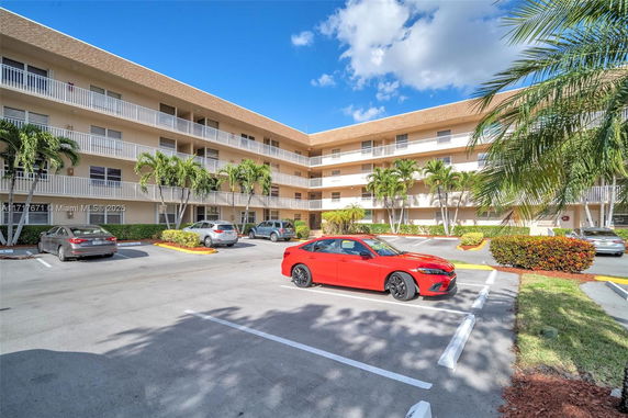 Outdoor parking area in front of a multi-story building with balconies.