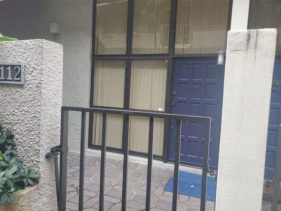 Front view of a building entrance with a blue door and large windows.