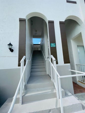 Front view of a building with stairs leading to an upper level through an archway.