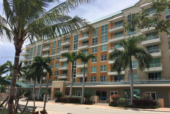 Front view of a multi-story building with balconies and palm trees.