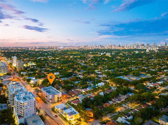 Aerial view of a cityscape with a mix of residential and commercial buildings, highlighted location marked on one building.