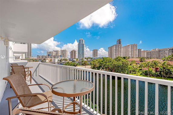 Balcony view from a high-rise apartment overlooking a body of water and surrounding skyscrapers.