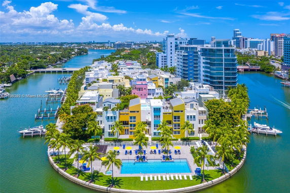 Aerial panoramic view of a vibrant waterfront residential area with a swimming pool and colorful buildings.