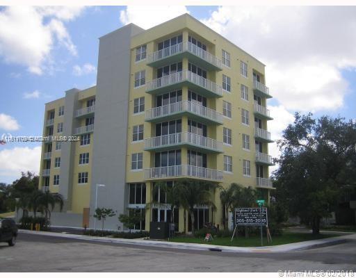 Front view of a multi-story residential building with balconies and yellow exterior walls.