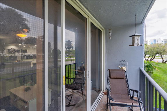 View from a balcony with a lounge chair and bird feeder overlooking green areas.